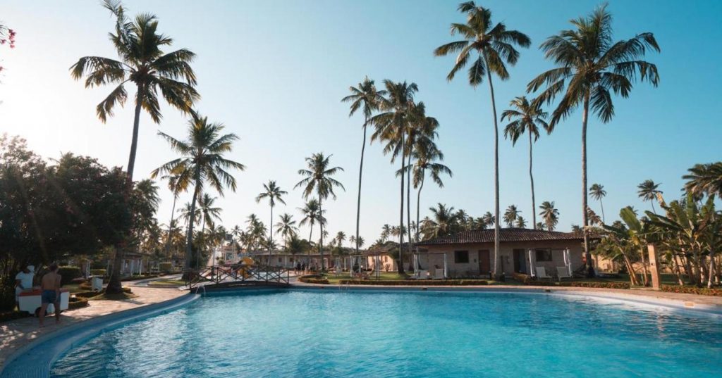 Nos resorts no nordeste, uma grande piscina no cetro, cercada por uma casa particular e palmeiras