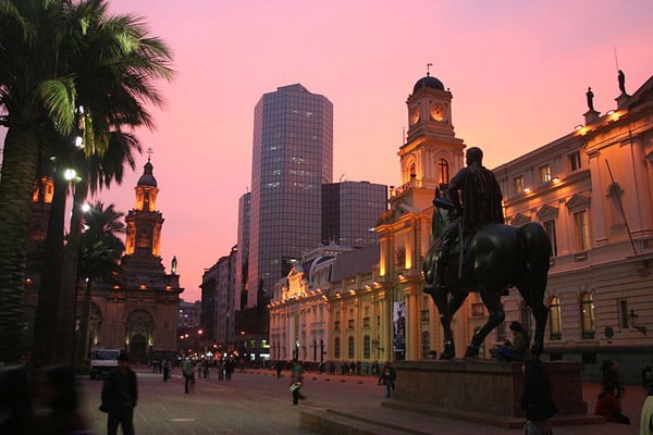 A plaza de armas, sob o pôr do sol alaranjando com construções coloniais em pontos turísticos no chile